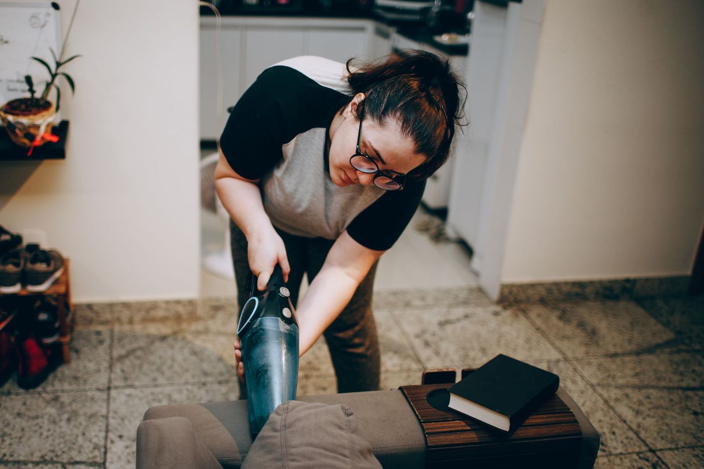 A cleaner vacuuming a sofa in a warm, lived-in home